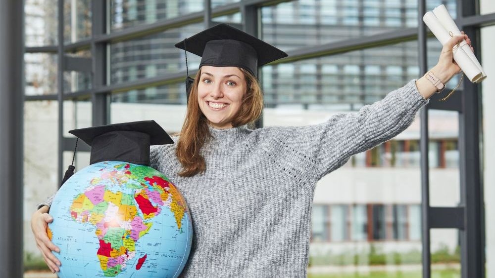 Foto einer Absolventin mit Globus im Arm